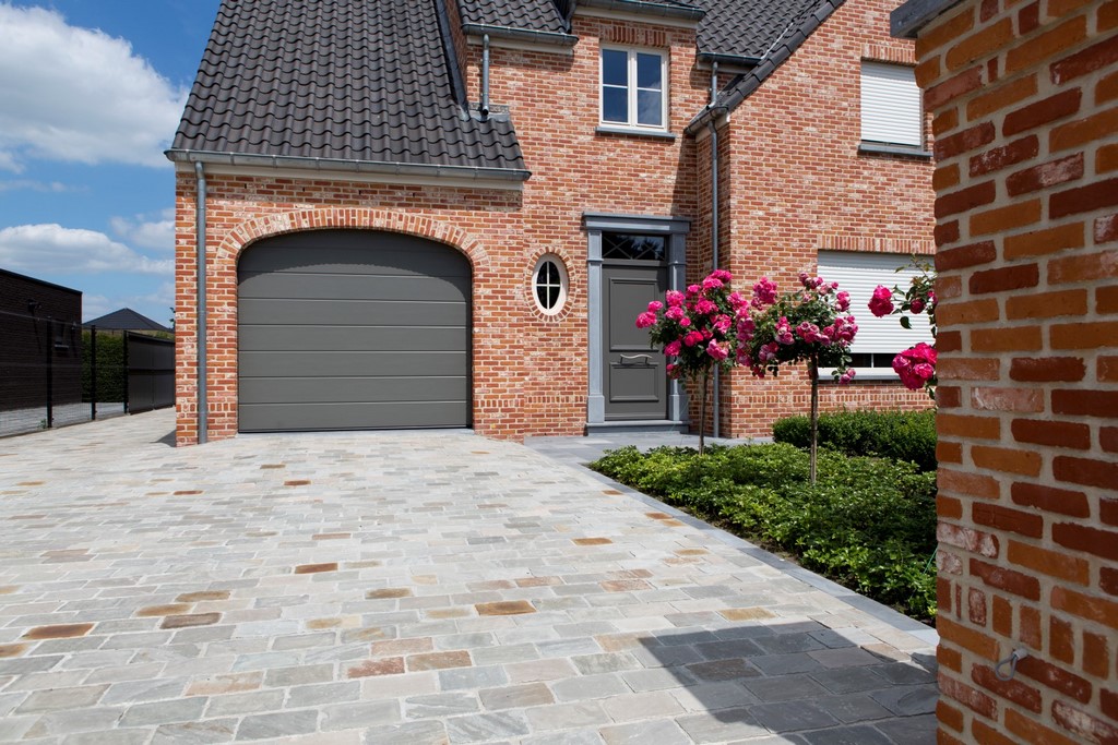 Buitenaanzicht van een woning met een grote oprit uit natuursteen.